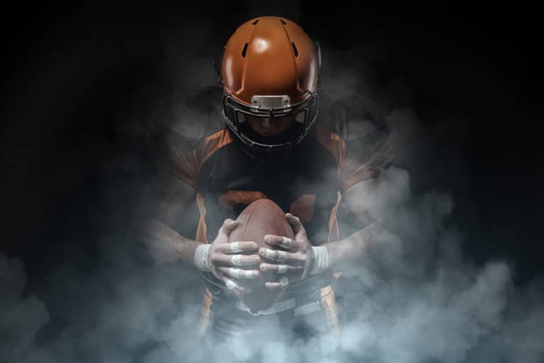 Football player with orange helmet and smoke rising behind him.