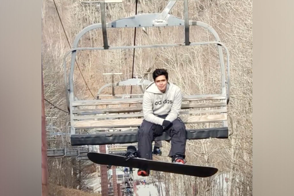 Man with snowboard on a ski lift. 