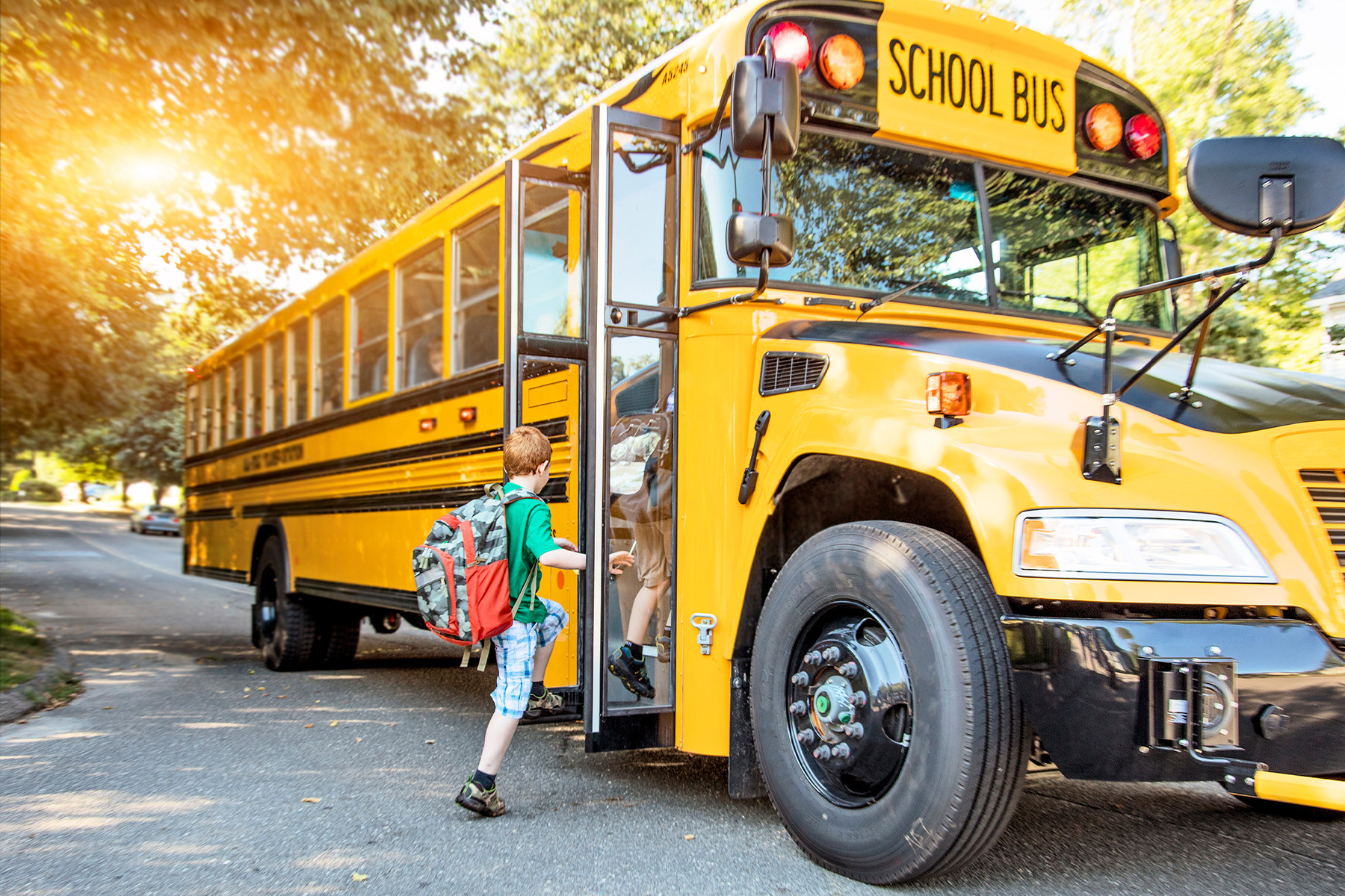 A child boards a yellow school bus.