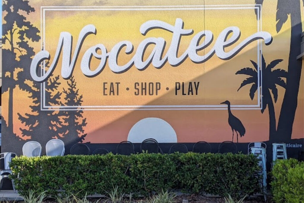 Large sign in yellow and pink that says Nocatee. 