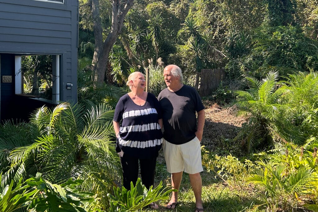 Couple stands outside their home in the sun.