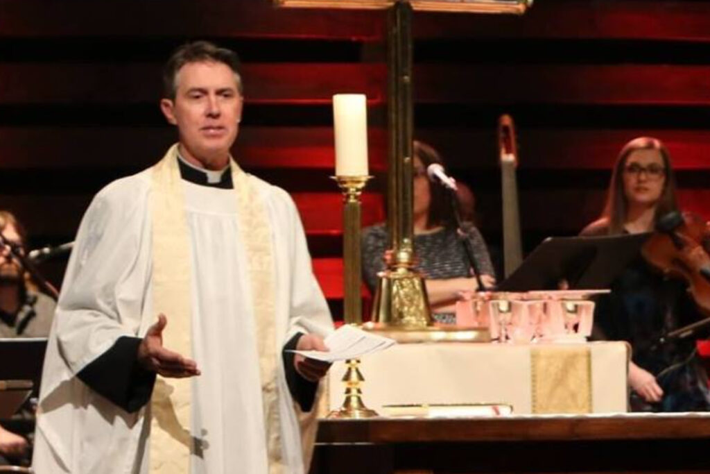 Pastor wearing a white robe at the dais of the church.