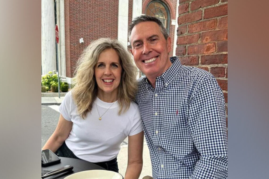 A couple smiling as they sit at a table.