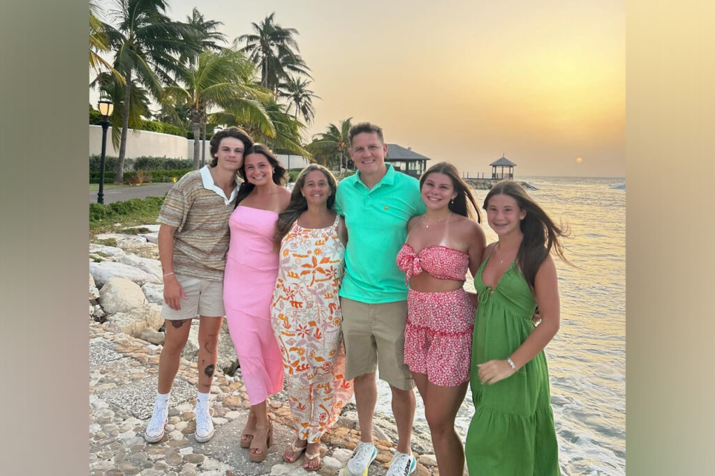 A family in various shades of pastel pose on the beach.