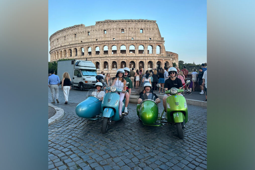 Four people on Vespas in front of the Coliseum.