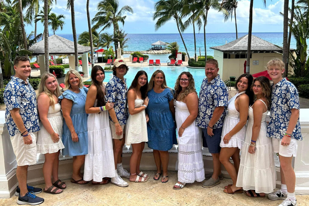 Family poses by a resort pool in a tropical destination. 