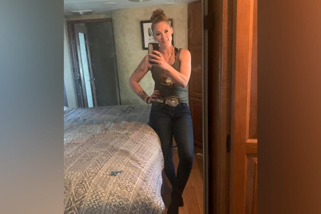 Woman stands in front of a mirror and takes her selfie.