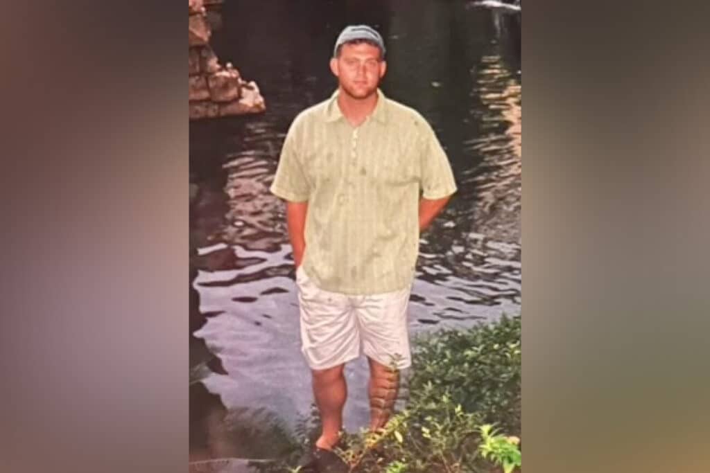 Man in a yellow shirt stands in water.