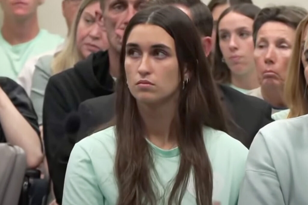 Young woman wearing a teal shirt in a courtroom.