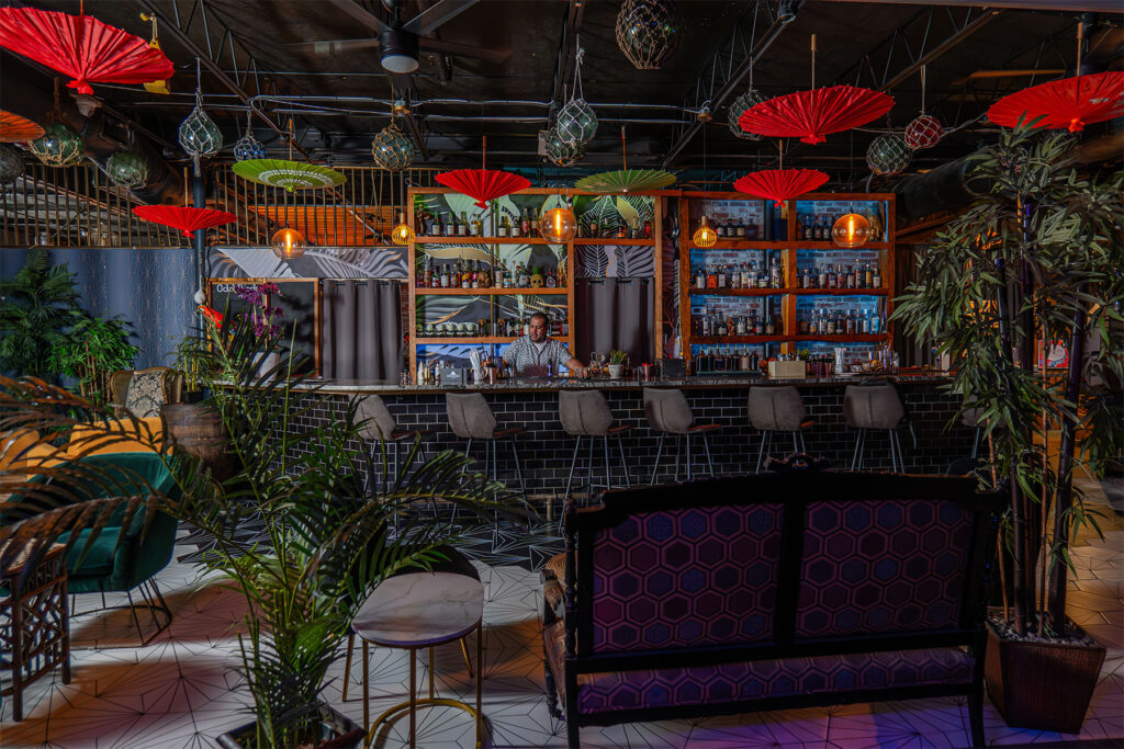 Bar with red umbrellas and plants.