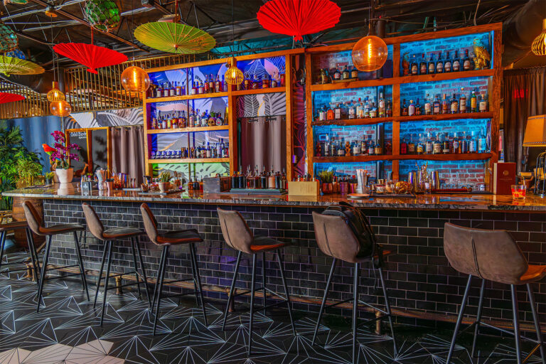 Bar with chairs and red umbrellas hanging from ceiling.