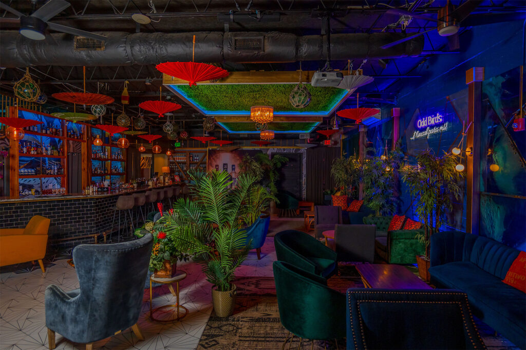 Bar with grass and red umbrellas hanging from the ceiling.