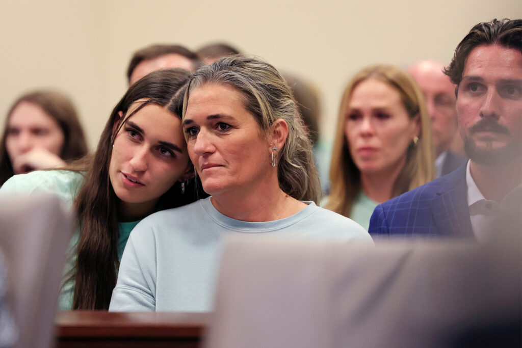 Woman rests head on her mother in courtroom.