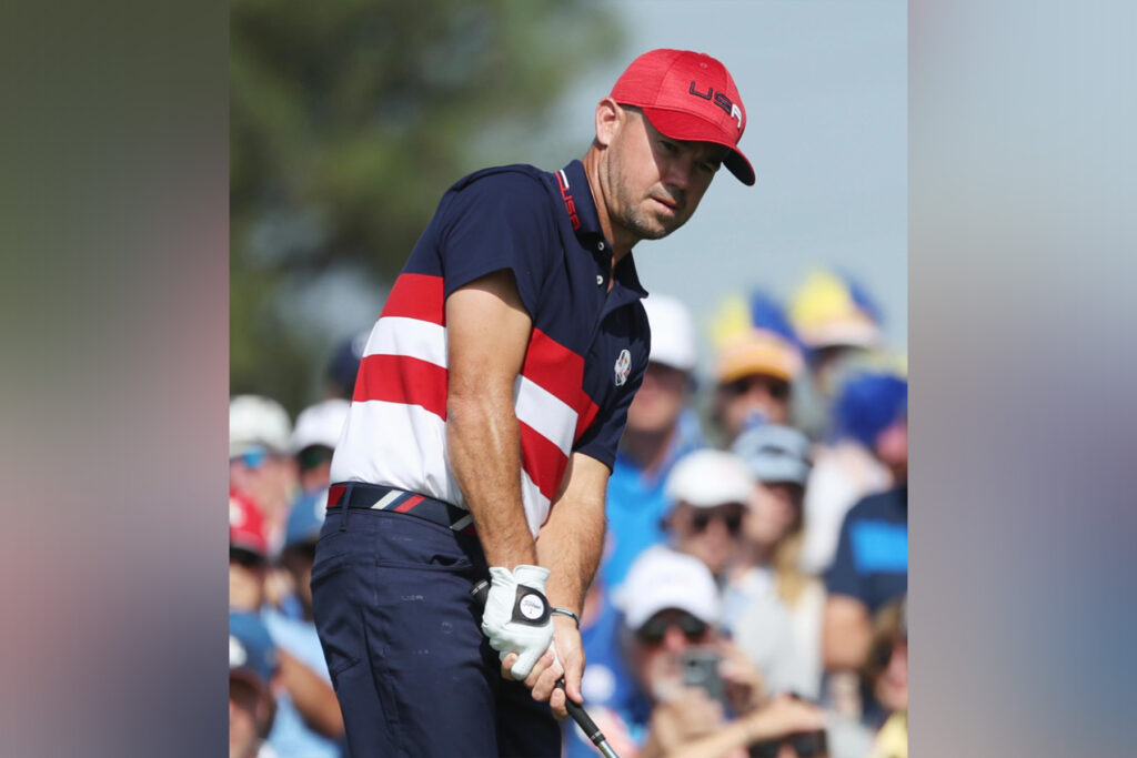 Brian Harman wearing a red hat and holding a golf club.