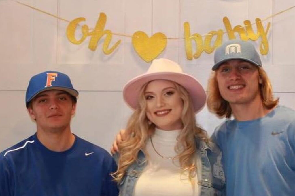 A woman wearing a pink hat flanked by her brothers.