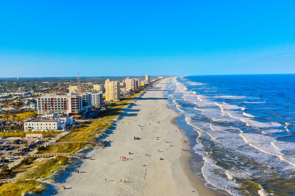 Aerial view of Jacksonville Beach shoreline dotted with people.