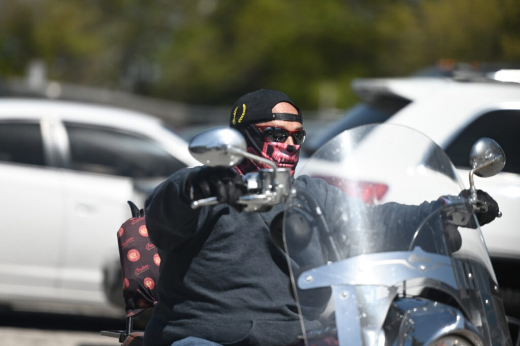 Man wearing gator on a motorcycle.