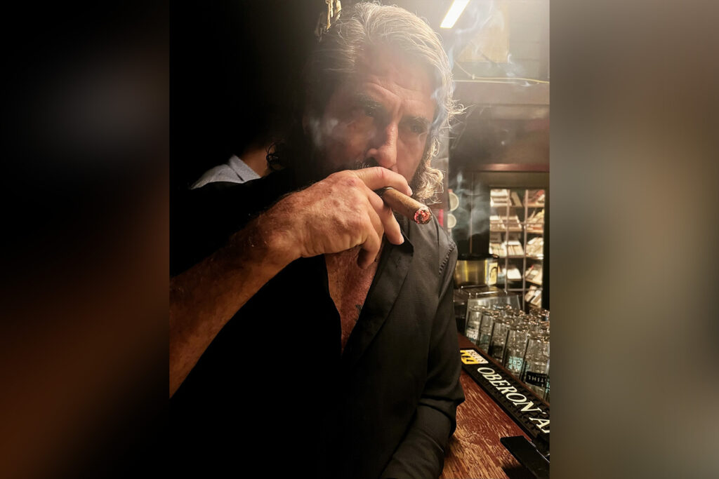 Man with gray hair smoking a cigar.