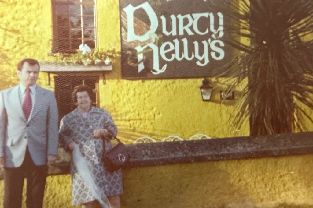 Couple stands in front of a yellow pub in Ireland.