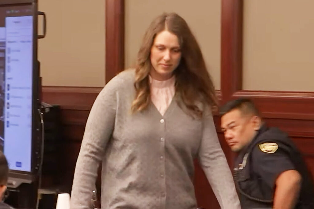 Woman wearing gray sweater in a courtroom.