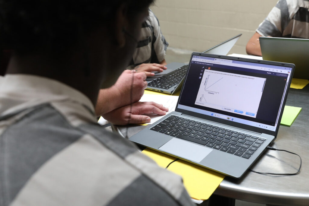 A student with a laptop in a jail classroom