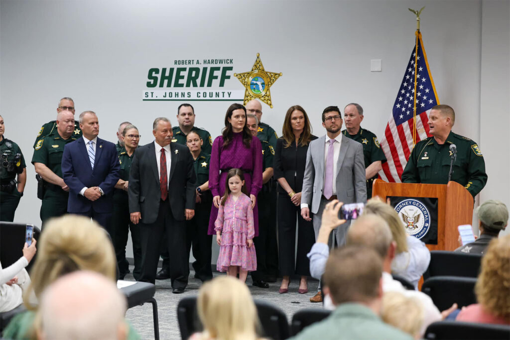 Man at podium flanked by a dozen officials.