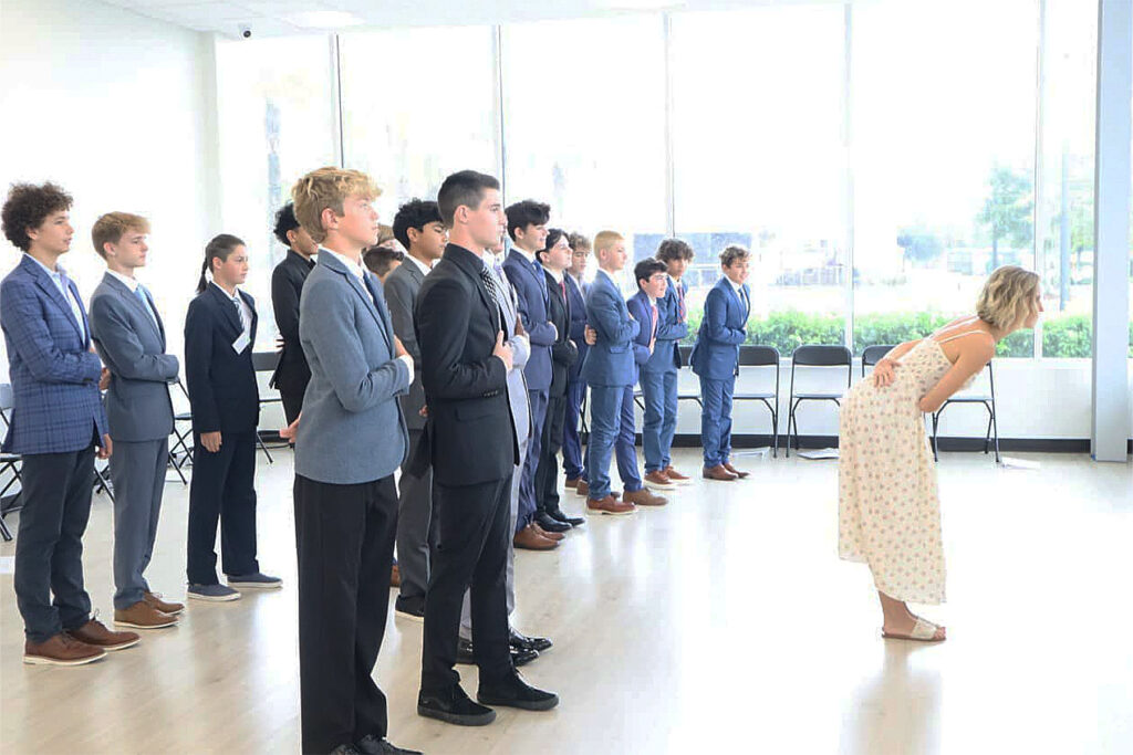 Woman instructs men dressed in suits.