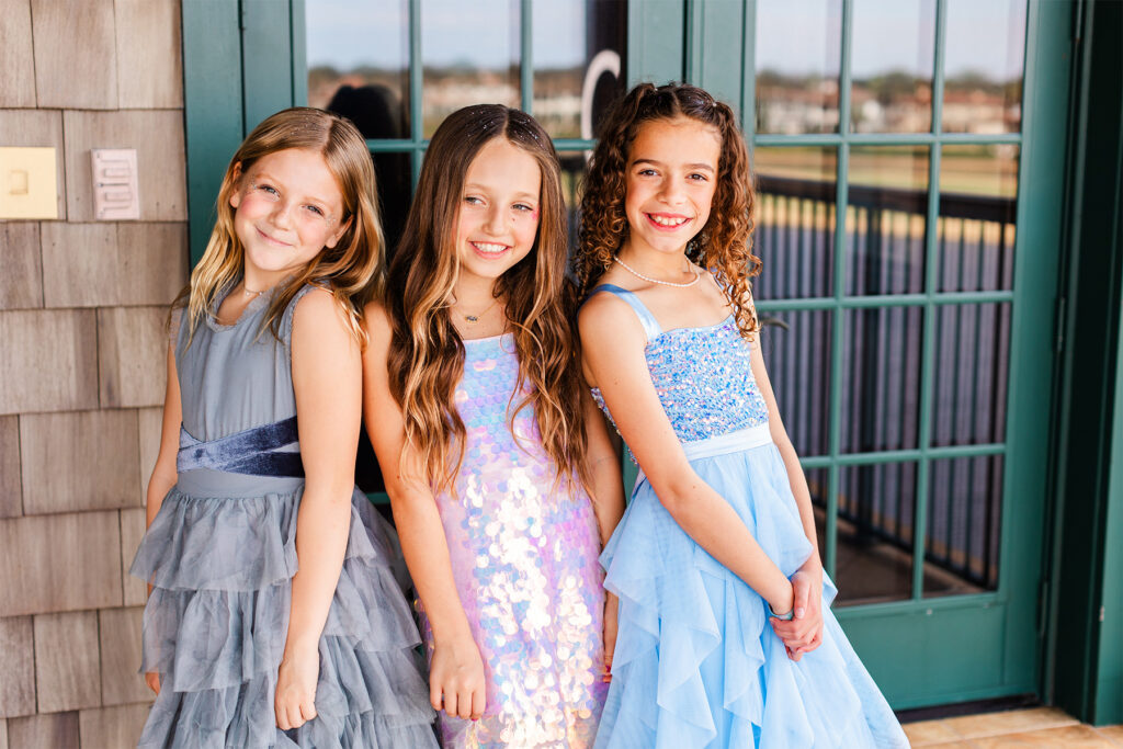 Three young girls in formal dresses.