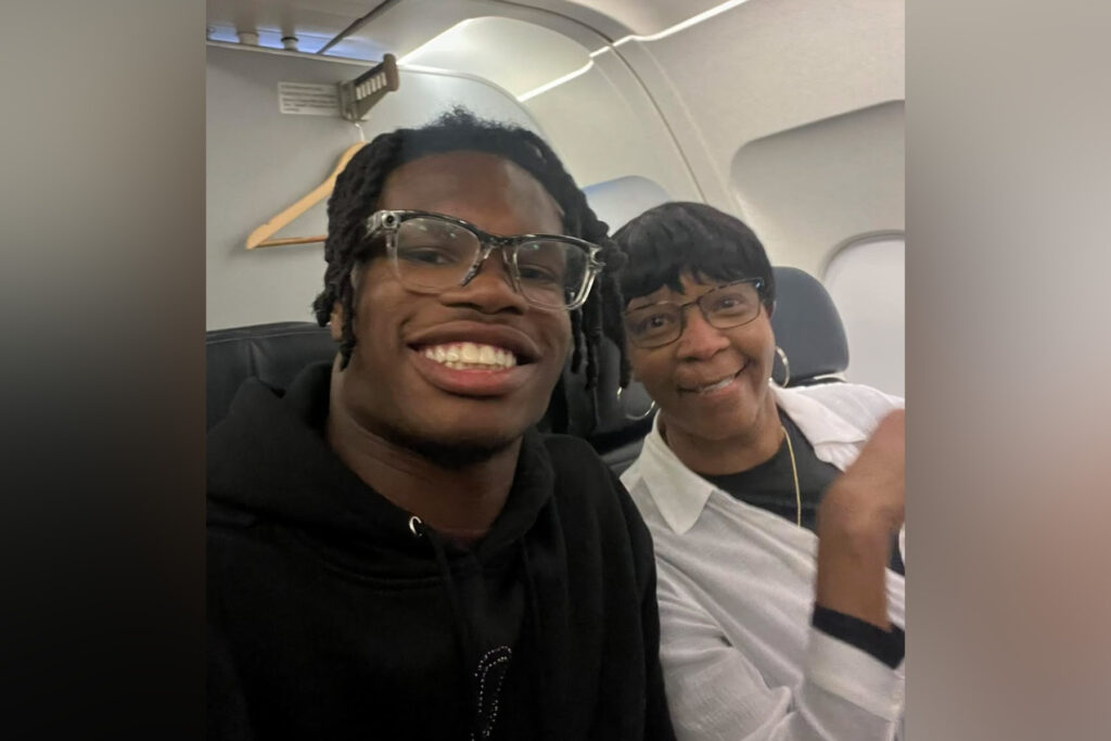 Travis Hunter smiles next to an older woman on an airplane.