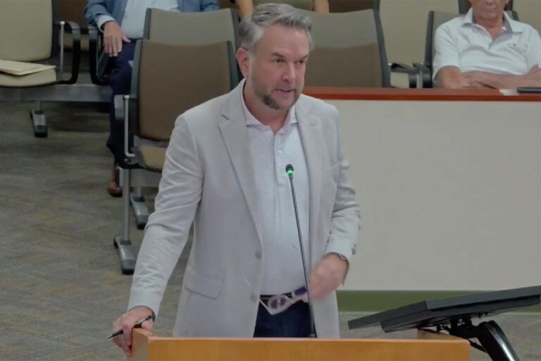 man speaking at meeting.
