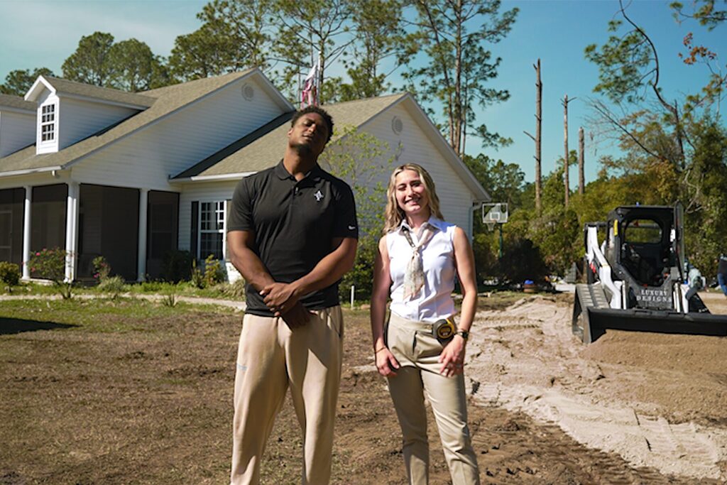 Man in black shirt and woman pose outside near a Bobcat.
