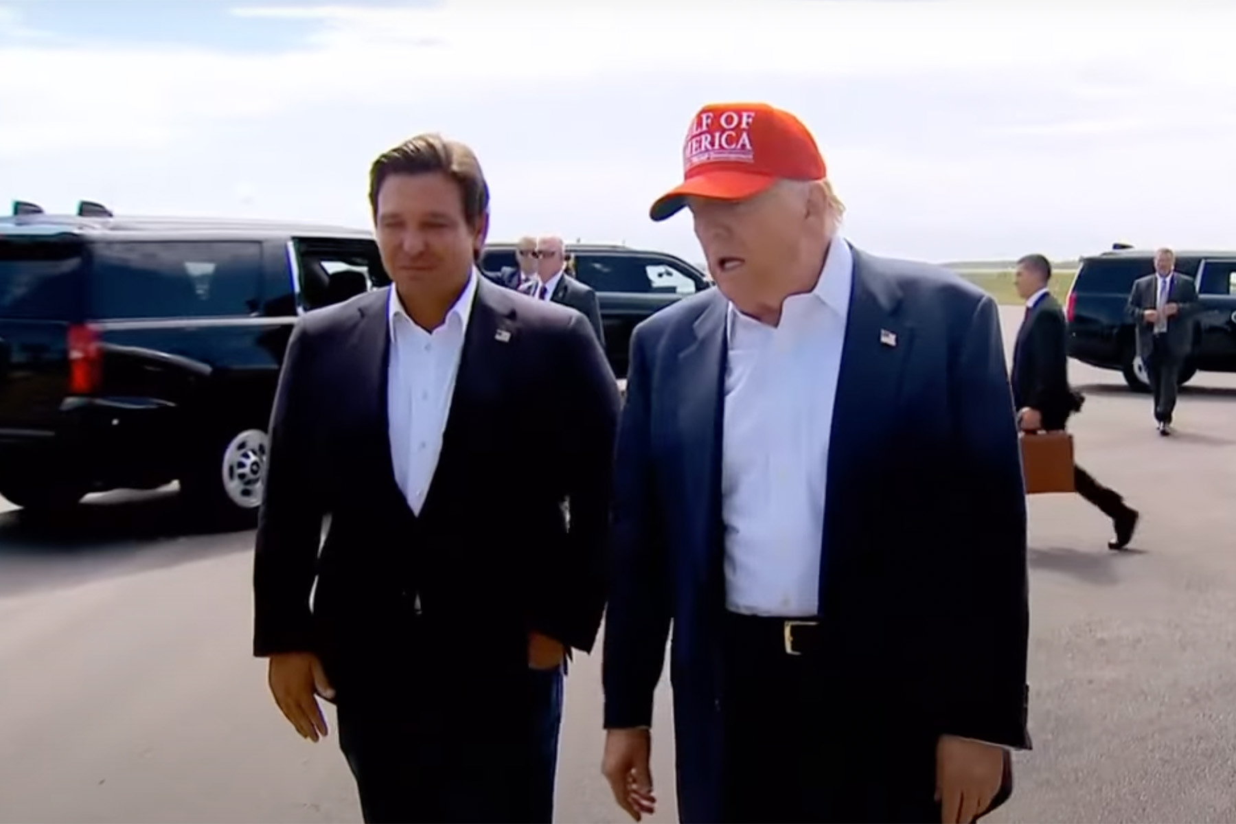 Ron DeSantis and President Donald Trump walking near an ICE facility.